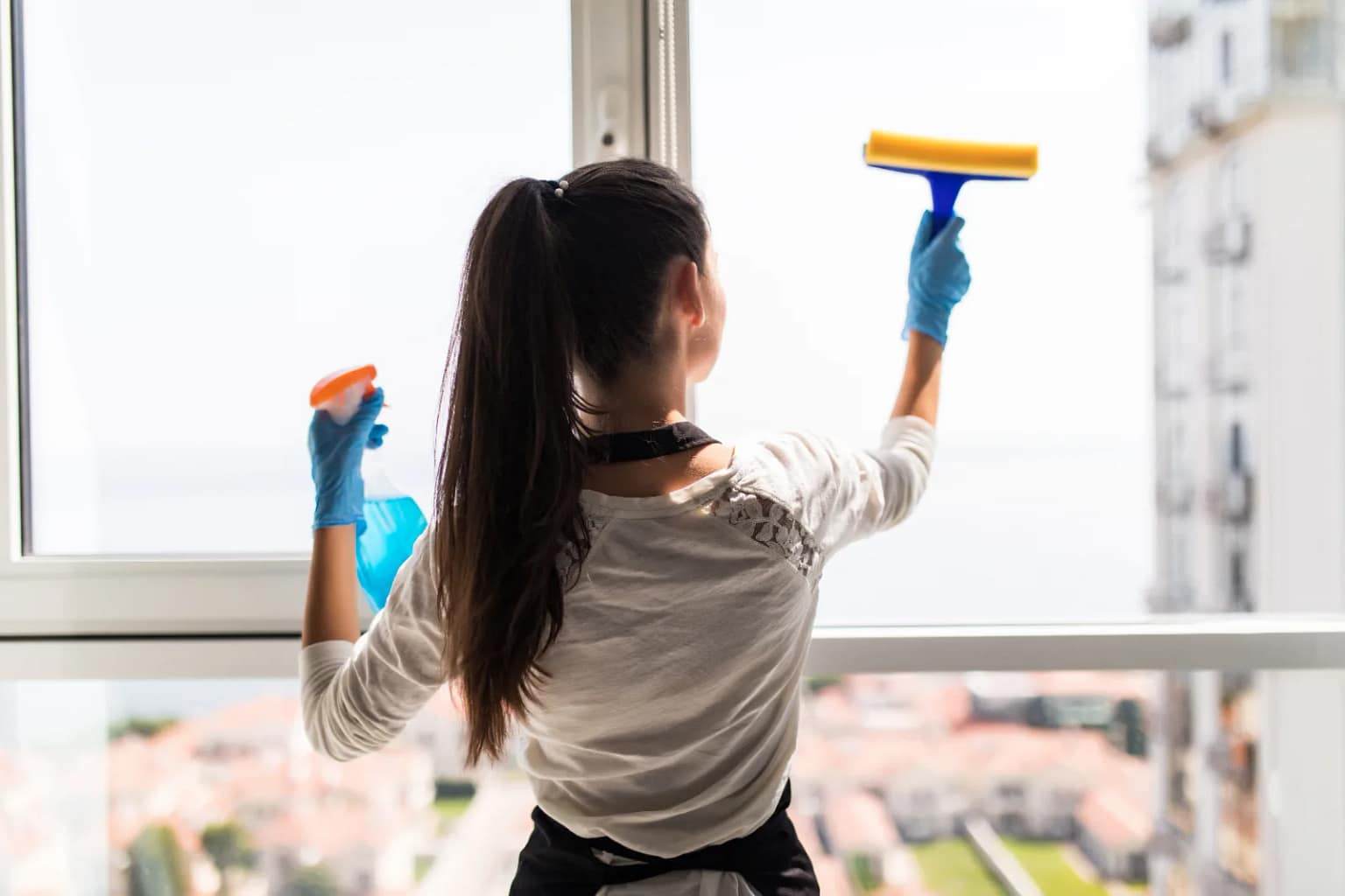 Home 41 Come pulire i vetri senza aloni: donna che lava la finestra